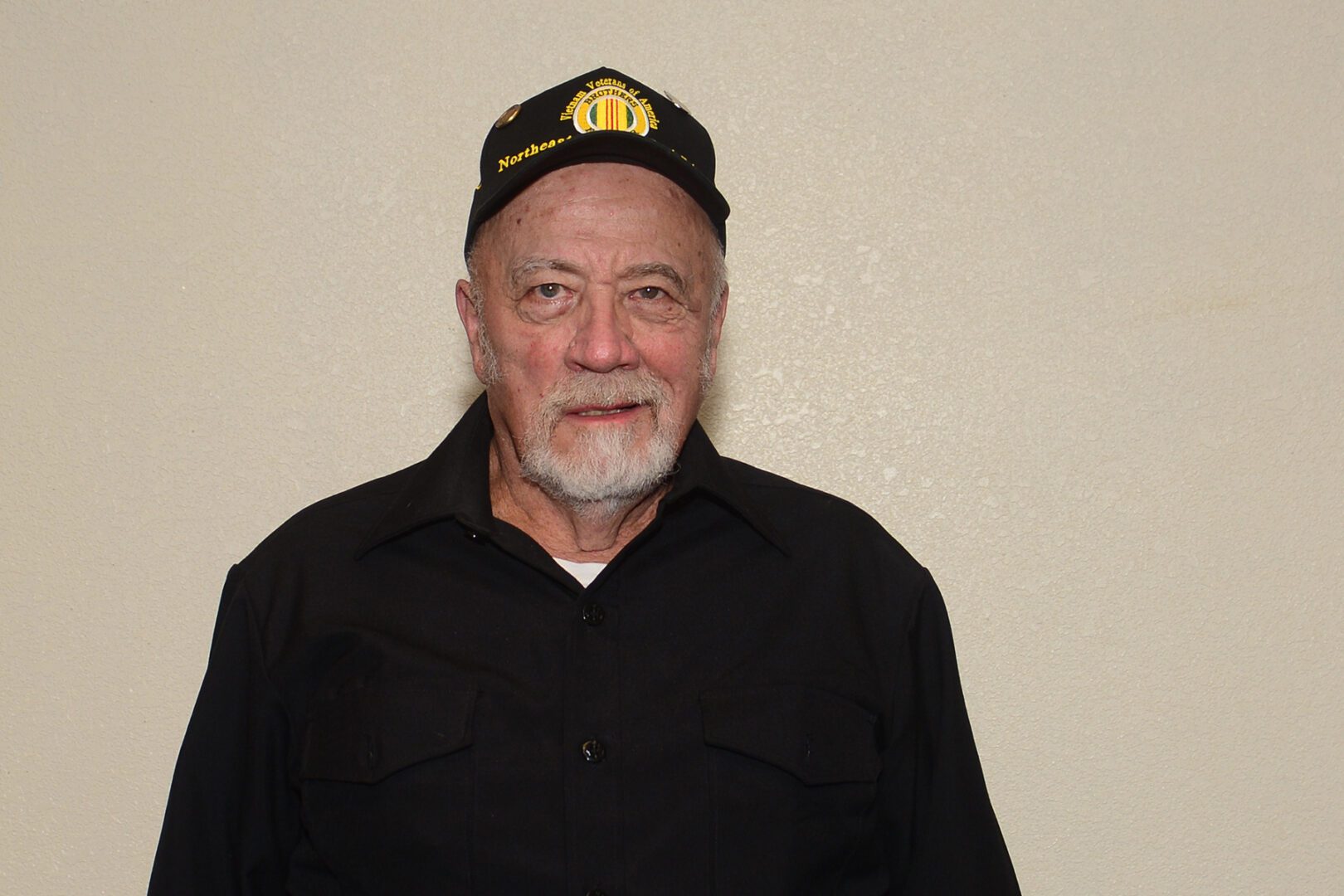 A man in black shirt wearing a hat.